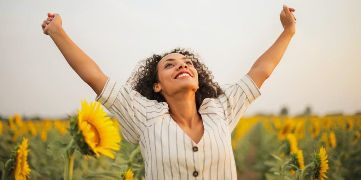 Woman with arms extended to the sky in a field of sunflowers
